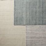 Top-down view of rug edges overlapping other rugs in complementary neutral and blue shades