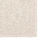 Corner close-up highlighting high-low pile texture and detailed woven border of cream rug
