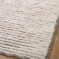 Top-down view of rug corner on wood floor emphasizing the dense pile and subtle color pattern