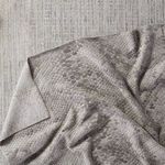 Rug draped over a blue-toned woven floor covering, highlighting backing and fabric drape