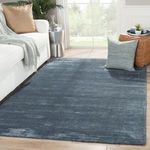 modern living room scene with dark blue ribbed rug under sofa, pillow, and pouf by large window