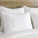 Close-up of smooth white duvet pillows against wooden headboard