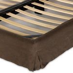 Close-up of wooden slats and black metal frame within brown linen slipcovered bed base