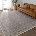 Rug placed in living room setting next to tan leather sofa, white walls, and wooden flooring