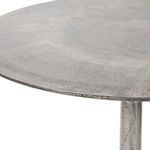 Close-up of round metal tabletop edge with finely textured surface and subtle sheen