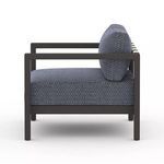Side profile view displaying chair’s thick seat cushion and bronze armrest frame
