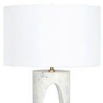 Upper half of lamp showing smooth natural linen shade and brass finial on white marble base