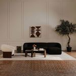 Faye sectional styled in a room setting with neutral walls, artwork, rug, wooden tables, and large potted plant
