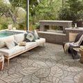 Outdoor patio setting with the rug beneath sofa and table, showing scale and natural context