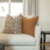 Rust pillow paired with floral print pillow on cream sofa with beige curtains