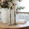 Pair of Bristol candlesticks styled on round wooden table with flowers in white vase and books in background