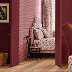 Button Spot Pink & Red wallpaper applied on bedroom wall with floral bed linens and wooden floor