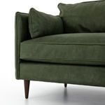 Elegant almond-finished wooden tapered leg beneath sleek leather sofa arm