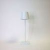 White table lamp from front without light, showing subtle shadow on wall behind