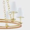 Double-ring chandelier with upper aged brass ring and lower natural rattan wrapped ring, topped with linen shades on cream...