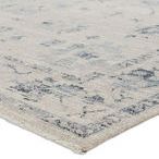 Close-up on corner showing low pile texture and woven edges of blue gray floral rug