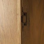 Interior door latch mechanism attached to wood panel inside cabinet door.