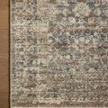 Top corner of rug highlighting detailed pattern with blue and brown floral elements and woven border