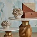Boxes styled on paired marble and wood tables against watercolor wall