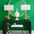 Gold hammered ball placed on a white cushioned bench with black metal frame against a green wall