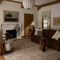 Milena Ivory Sand Rug shown on terracotta tile floor in a cozy living room with dark brown sofa and marble fireplace