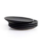 Stack of four matte black ceramic salad plates viewed from an angle showing layered arrangement