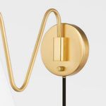 Close-up of gold circular wall mount with black cord and small round switch