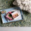 Close section of rug with tray holding books and candle, showing yarn texture and color variation