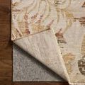 Corner of rug lifted to reveal woven backing and edge stitching on hardwood floor