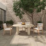 Arranged Luce dining chairs with ivory cushions around rounded stone outdoor dining table under tree shade