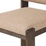 Close-up of padded seat upholstery with rounded corners and dark wood frame edges