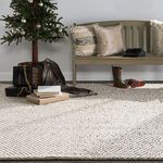 Rug under Christmas tree with wrapped presents and wooden bench with neutral pillows