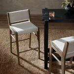 Pair of stools at a black table with sunlight casting shadows on the floor and boucle upholstery visible