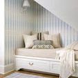 Brett lumbar pillow displayed with other neutral cushions on built-in beige daybed under angled ceiling