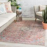 Wicker indoor seating area with rug covering floor between sofa and armchair