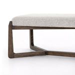 Close-up on wood frame leg showing warm brown finish and wood grain under the upholstered seat