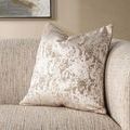 Styled living room setting with sofa featuring decorative beige and gold textured throw pillow