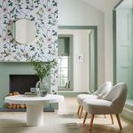 Nuit Wallpaper applied in a bright room around a fireplace with green trim and modern white chairs