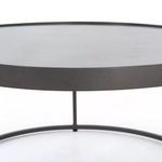 Close-up of slim iron supports between two round table tops stacked
