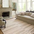 Ivory clay rug styled in a sunny living room with beige sofa, armchair, and large window natural light