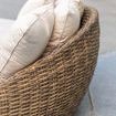 Side angle close-up showing wicker weave and arrangement of five plush cream pillows