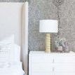 shagreen jet wallpaper applied in bedroom with beige upholstered bed and white nightstand with gold lamp