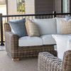 Outdoor porch view showing wicker sofa with cushions positioned near railing and surrounded by other furniture