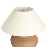 Top view of lamp shade showing metal harp and finial inside off-white fabric shade
