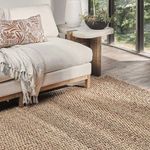 Styled indoor setting with beige jute rug under sofa near window and side table