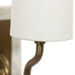 Lower edge of white linen shade and curved bronze arm connection on Calla Bookshelf Lamp