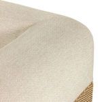 rounded cushioned armrest joining seat cushion with woven natural base visible underneath