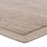 Close-up corner view showing the layered texture and edges of the light brown handmade rug