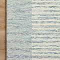 Square close-up of rug edge highlighting woven wool texture and soft coloration