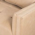 Close-up of button-tufted armrest upholstery with soft leather folds